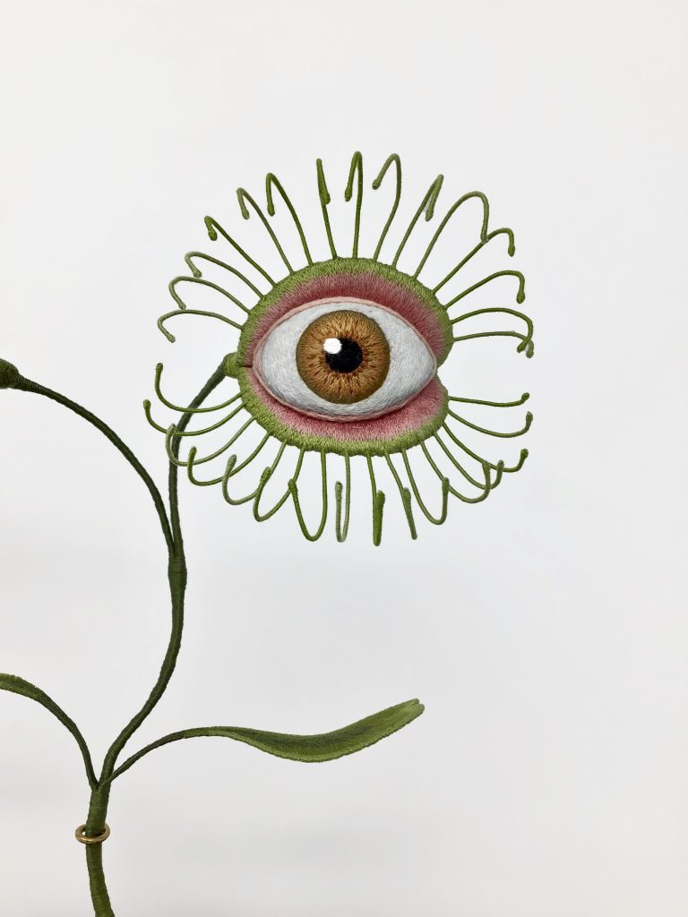 an embroidered sculpture of a venus fly trap, but with an eye where the fly trap would be