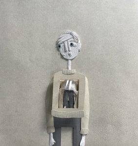 A papercut collage in shades of grey. The collage is of a thin, androgynous figure, looking worried. They're wearing a sweater and jeans.