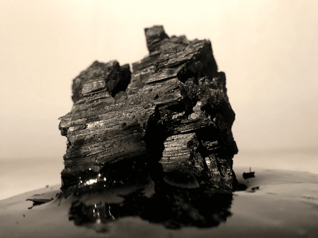 A photo of what might be a huge craggy rock in a landcape, or alternatively a close-up of a grain of rock or sand, in greys and pale pink.
