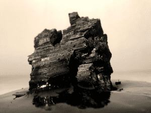 A photo of what might be a huge craggy rock in a landcape, or alternatively a close-up of a grain of rock or sand, in greys and pale pink.