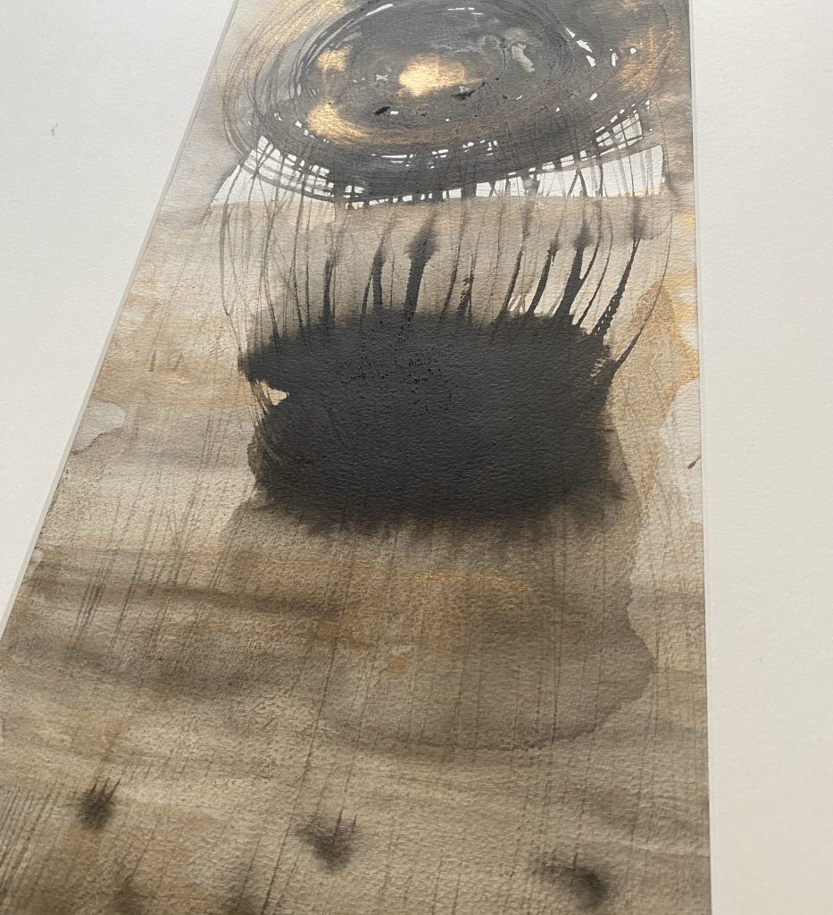 An image of a mixed media piece in watercolours, ink and botanic pigments, with pencil marks and metallic touches. The image is taken on a slant to show textures and details of the work.