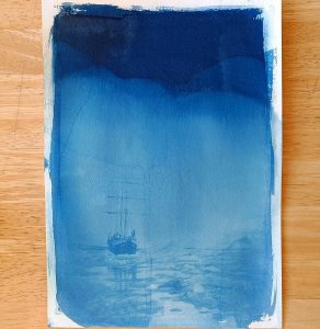 A double exposure cyanotype made from a photograph of the Arctic Circle. The picture has a graduated blue background, with a print over the top of the woodent Tallship' Antigua among sea ice.