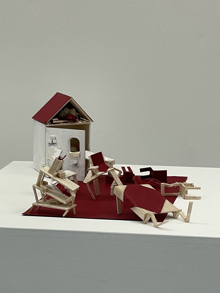 wooden model of a house with broken furniture spilling out