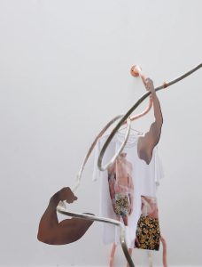 sculpture with two cut-out arms hung with a T-shirt printed with a torso