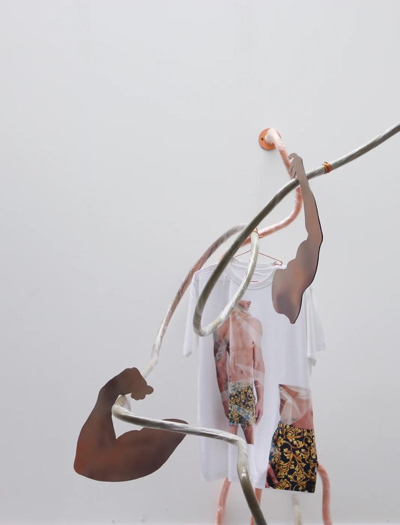 sculpture with two cut-out arms hung with a T-shirt printed with a torso