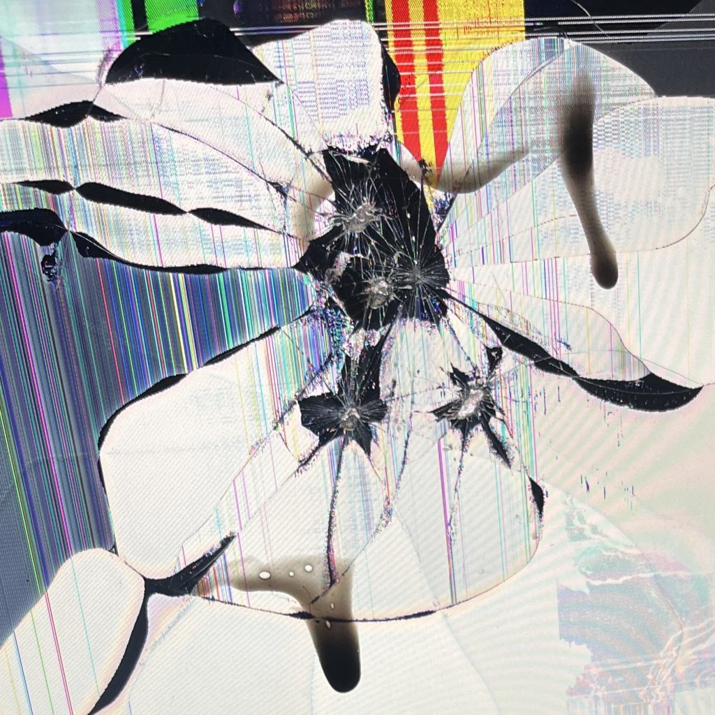 A broken screen with bright block colours almost like a chaotic web. There is also black liquid on top.