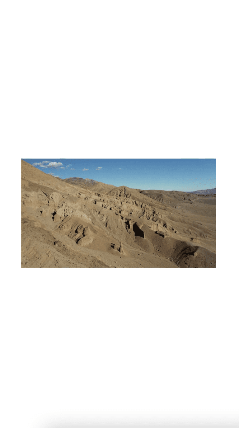 A still of an orangey red sand dessert dune sits in the bottom left corner of the screen with clear blue soup peaking out to the top left corner framed on a white background. The image is designed to be viewed like from a phone screen.