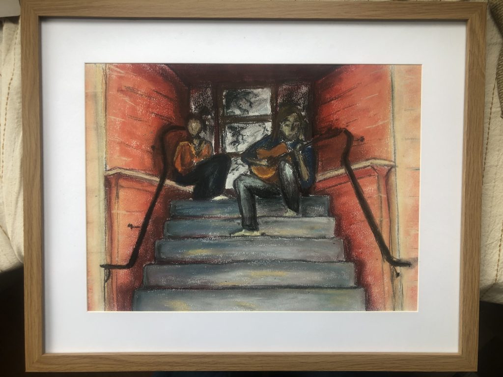 Framed drawing in soft pastels of two people sitting on a flight of steps at the entrance to an apartment building. The walls either side are a reddish brick colour and the steps are grey. The man sits on the top step on the right hand side, playing a guitar. The woman sits on the left hand side, slightly further back from the audience. The colours are warm and there is a dreamy, unfocused quality.