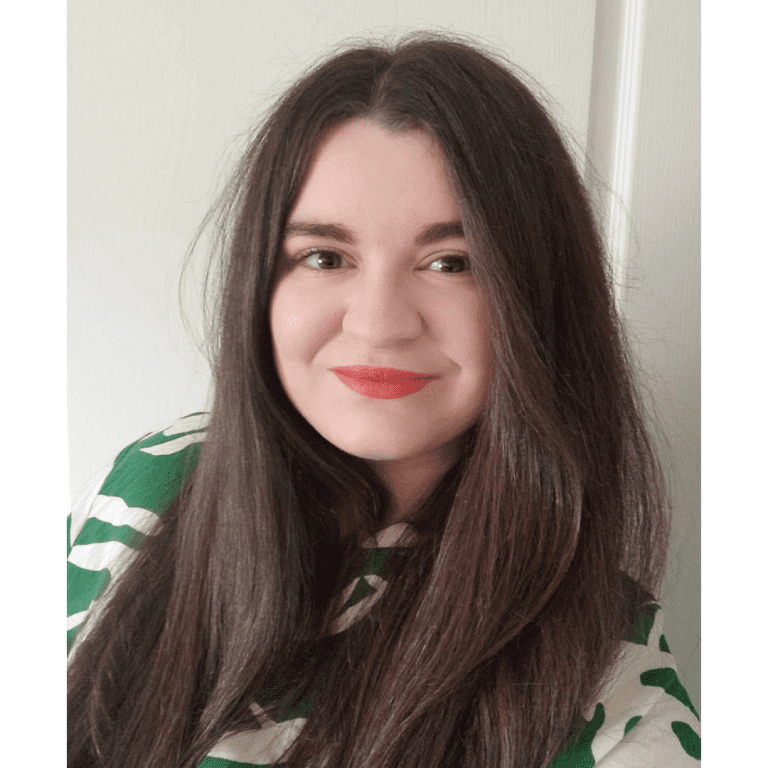 Picture of a woman with long brown hair, wearing a green and white top.