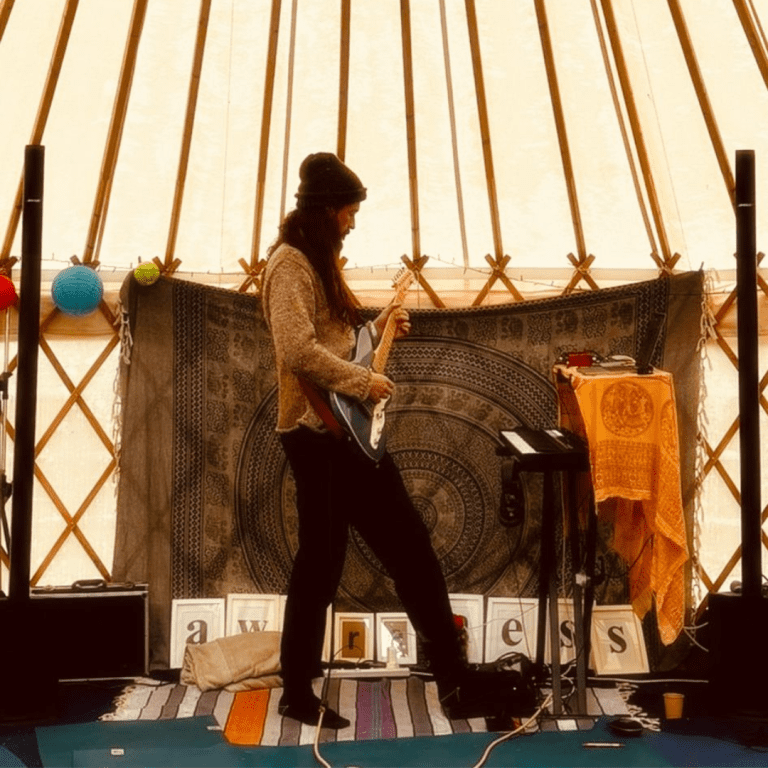 A man walks across a stage playing a guitar.
