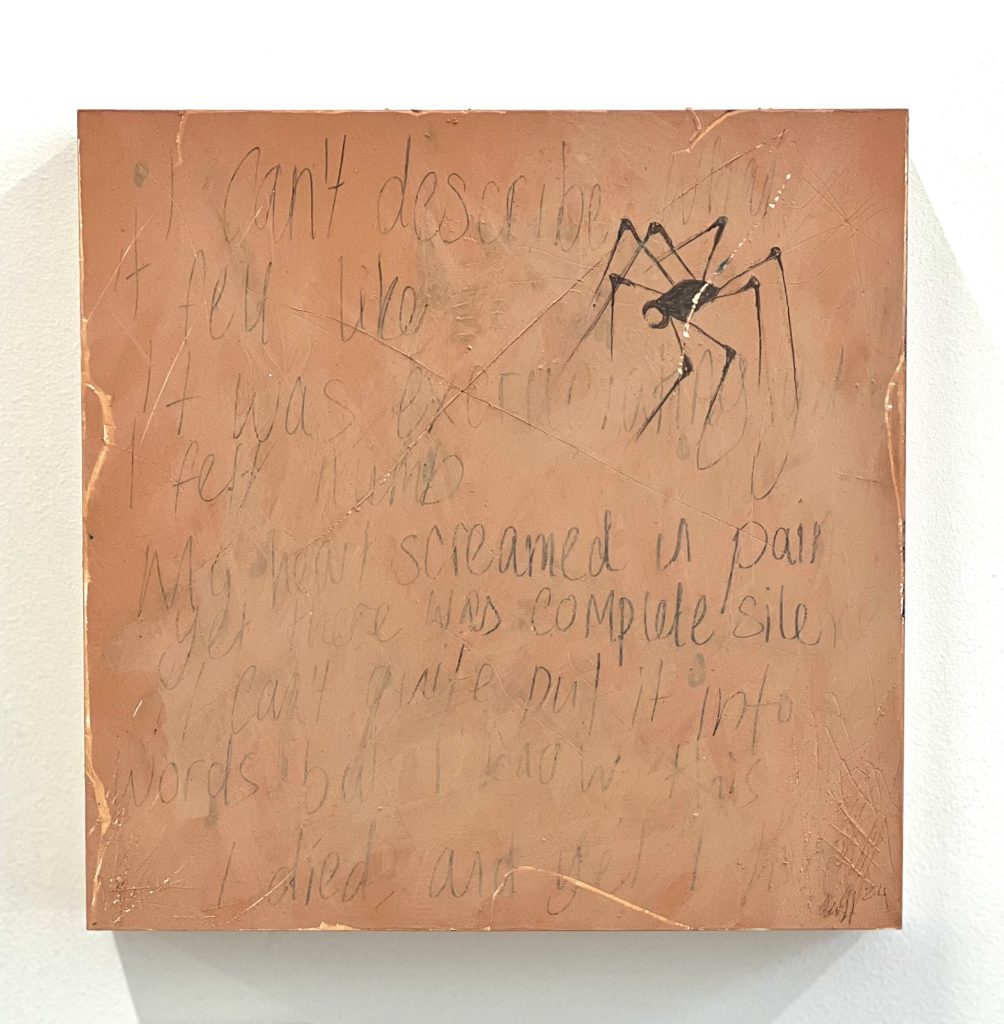 Pictured is a piece of square clayboard, painted in different shades of peach and pink. There are scratches across all the work, with text written in pencil. Some of the paint slightly covers the text. In the top right corner is a robot-looking spider, drawn in dark graphite. The text reads "I can't describe what it felt like it was excruciating yet I felt numb My heart screamed in pain yet there was complete silence I can't quite put it into words but I know this I died, and yet I live"