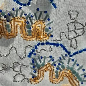 A close up image of a small beaded sculpture. It features curved natural shapes and bright colours on a sheer fabric background.