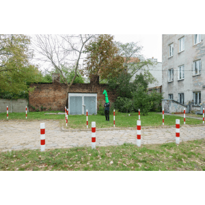 The artist, dressed up as a green-headed monster, standing in the middle of an urban setting in Poland.