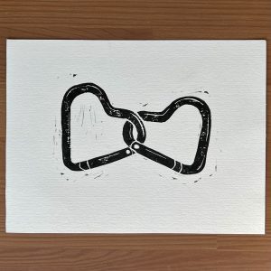 A black ink lino print of two interlocked, heart shaped carabiners.