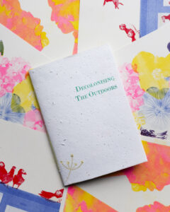 A zine entitled ‘Decolonising The Outdoors’ against a background of various prints from the artist’s series, Queer Ecologies.