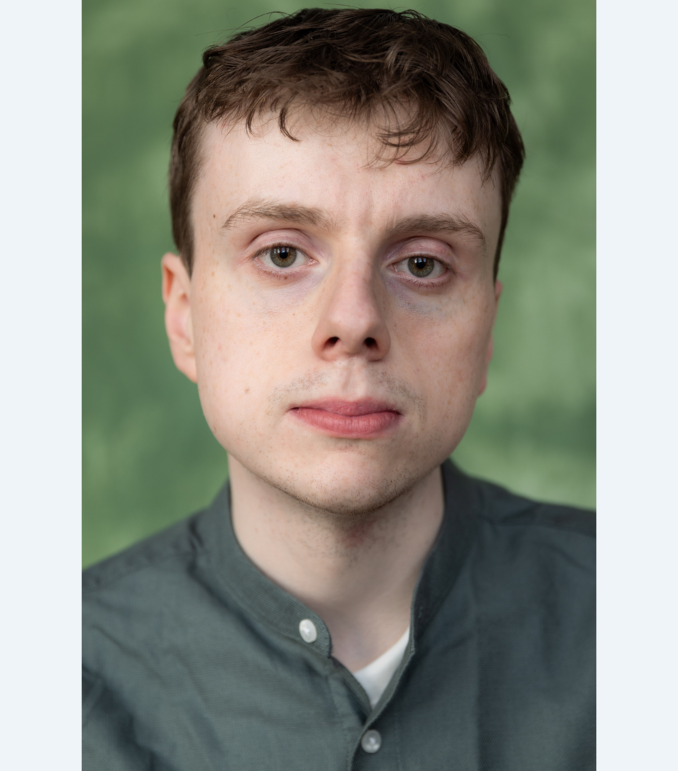 A young man with brown hair, with a green shirt and a white t-shirt underneath with a green background