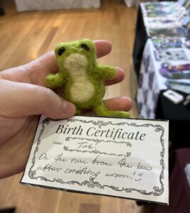 A hand holding a small felted frog