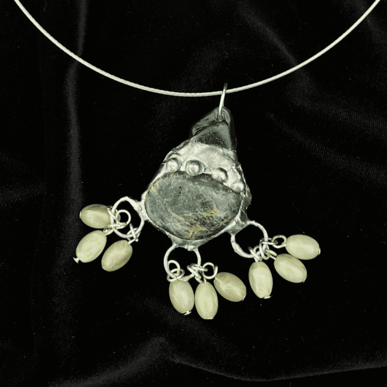 with soldered detailing and three dots on the metal. it is attached to green seaglass and has three sets of three small green beads at the bottom.