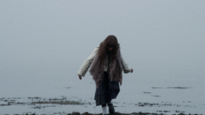 A woman walking by the sea on a misty day