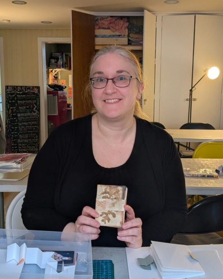 A middle aged white woman with grey hair, smiling