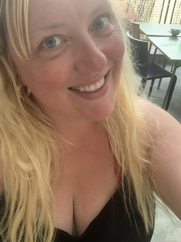 A close up selfie of Rachel who has long blonde hair and is wearing a black top.