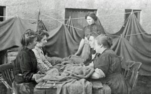 black and white photograph of island women sitting around a table, pounding fabric.