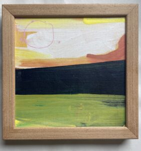 A small square abstract landscape acrylic painting on canvas in a light oak frame. A loose sky of yellow, cream, orange brushstrokes sits above a dark green-black hill band and a bright yellow-green field, with a thin pink circle drawn in the upper left like a sun.