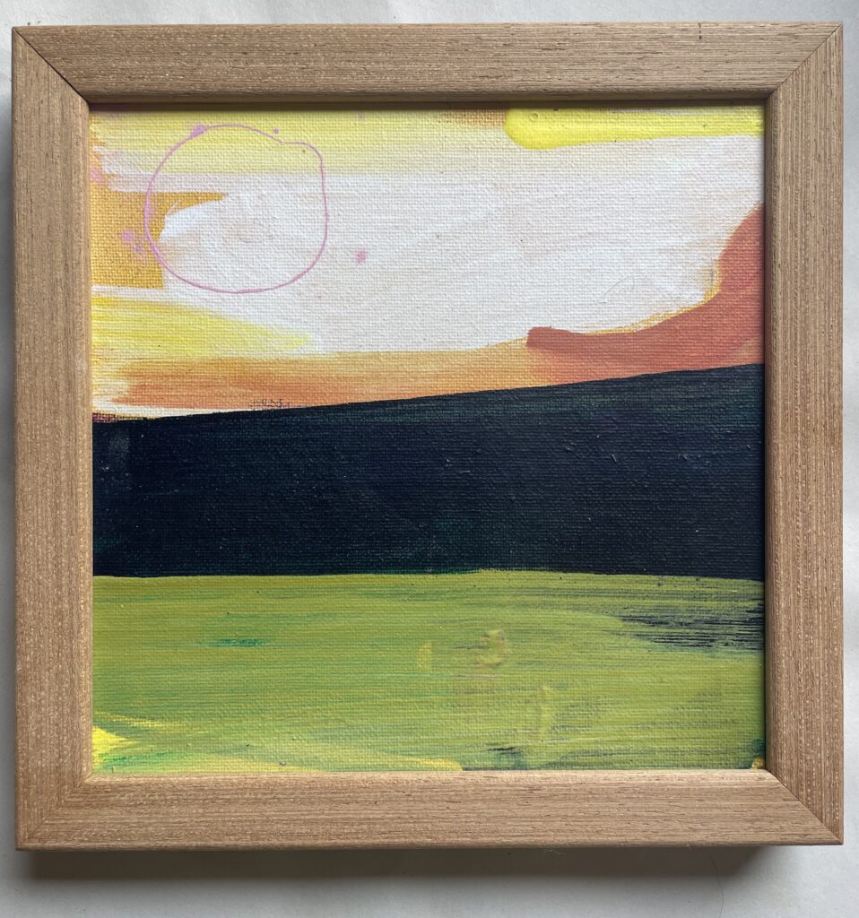 A small square abstract landscape acrylic painting on canvas in a light oak frame. A loose sky of yellow, cream, orange brushstrokes sits above a dark green-black hill band and a bright yellow-green field, with a thin pink circle drawn in the upper left like a sun.